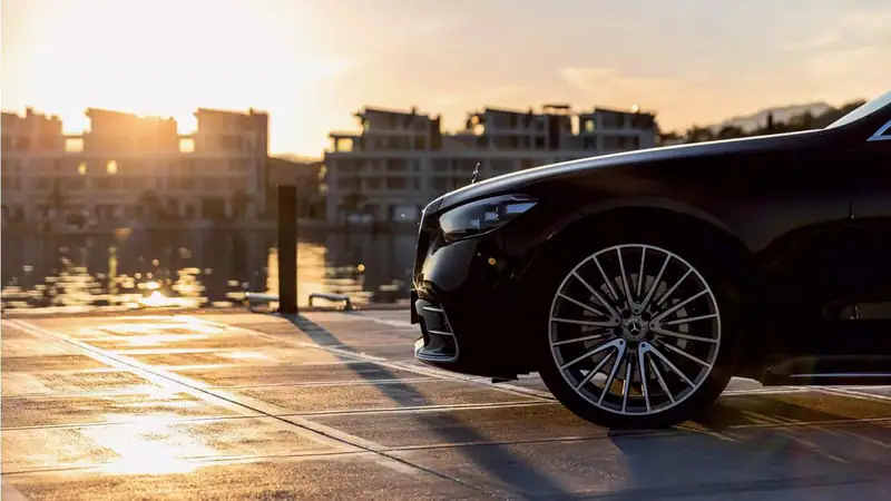 A premium black car waiting on the waterfront at sunset