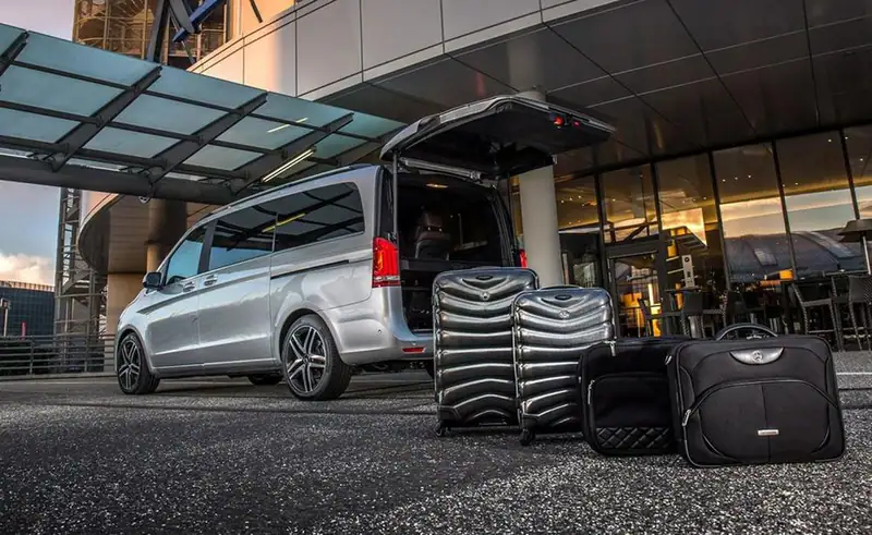 A Mercedes V-Class van with luggage at a hotel